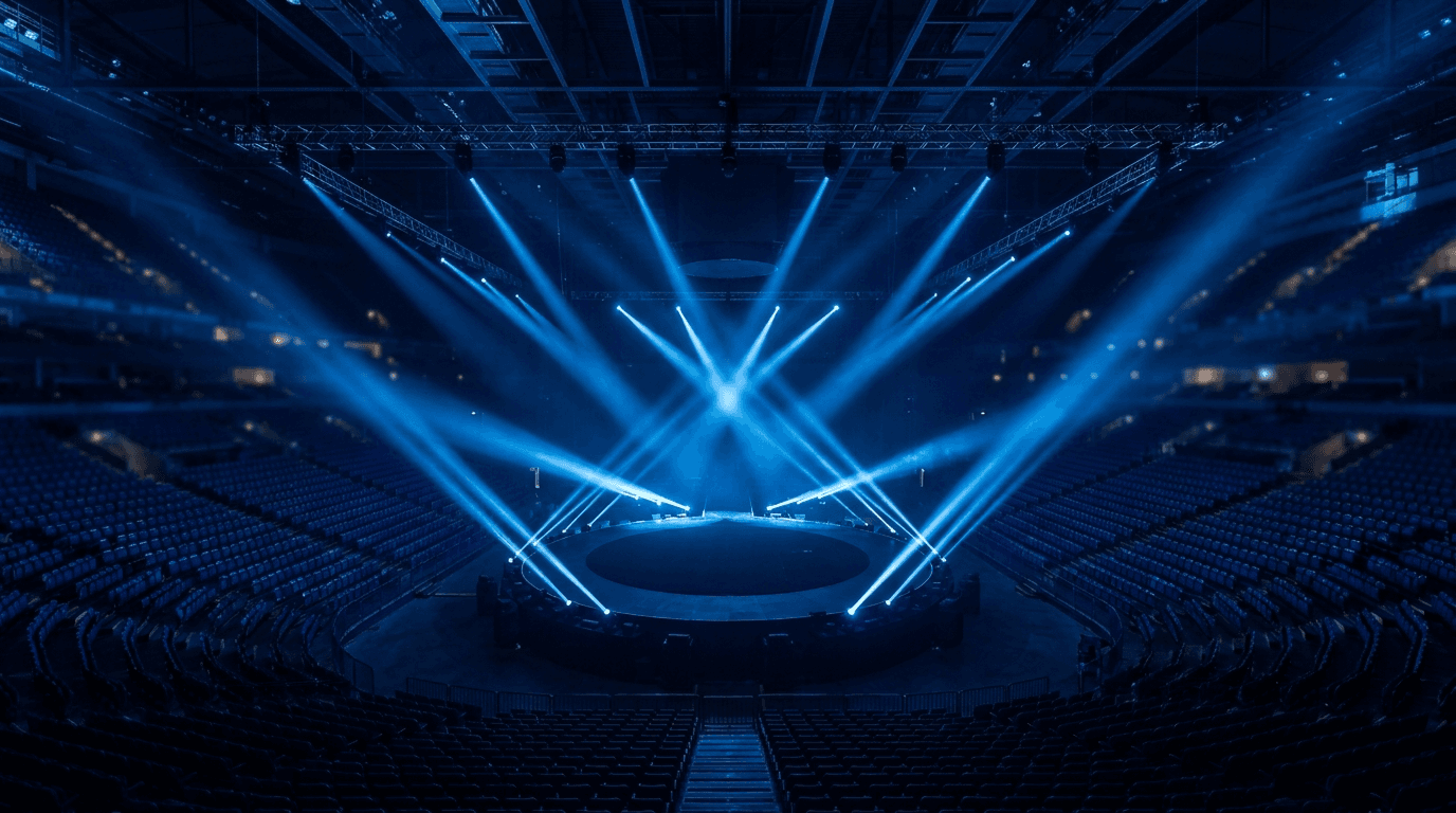 A massive arena with blue spotlights sweeping an empty central stage.