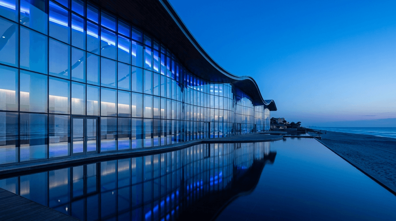 A modern beachfront convention center exterior glowing at blue-hour dusk.