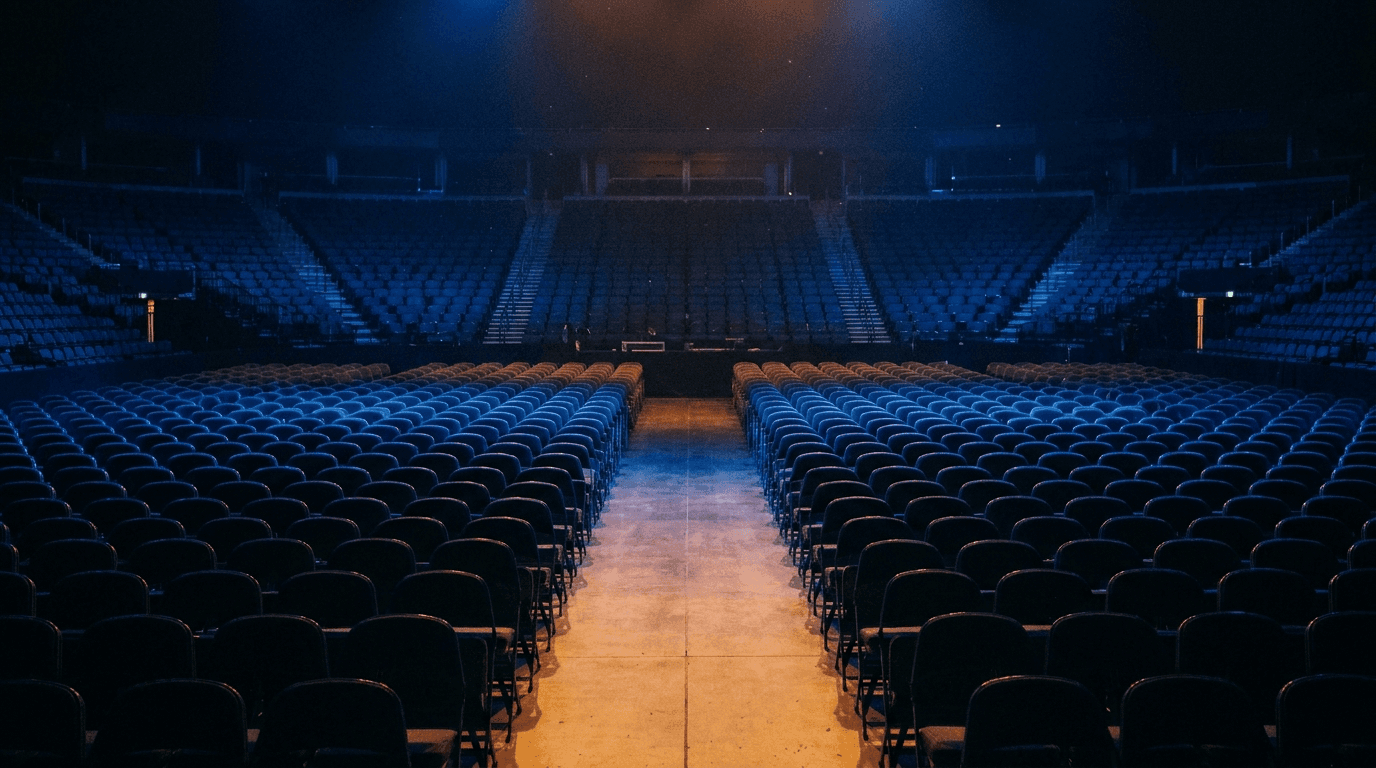 Rows of empty arena seating bathed in deep blue light before an event.